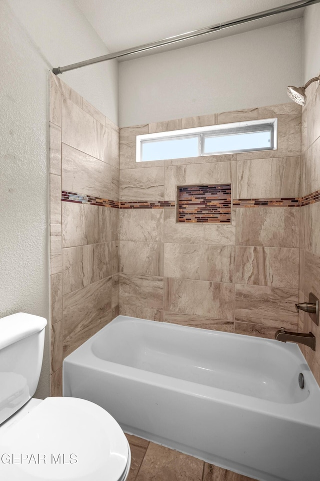 bathroom featuring toilet and tiled shower / bath