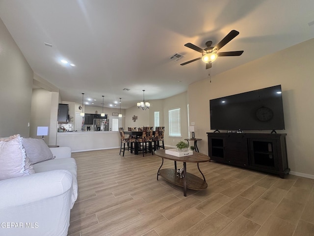 living room featuring hardwood / wood-style flooring and ceiling fan with notable chandelier