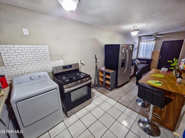 kitchen with light tile patterned floors, stainless steel appliances, a ceiling fan, decorative backsplash, and washer / clothes dryer