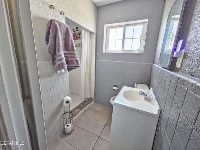 bathroom featuring tile patterned flooring, a wainscoted wall, vanity, tile walls, and a shower stall