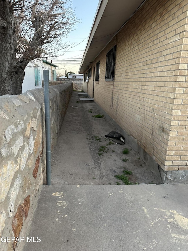 view of side of property featuring fence and brick siding