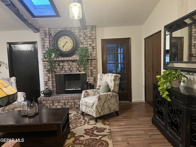 living room with hardwood / wood-style flooring, a textured ceiling, a skylight, and a fireplace