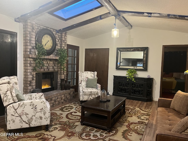 living room with hardwood / wood-style flooring, a textured ceiling, lofted ceiling with skylight, and a fireplace