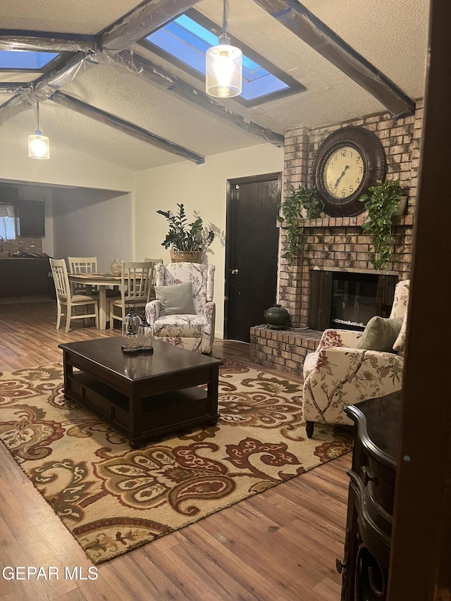 living room with a fireplace, a textured ceiling, lofted ceiling with beams, and wood-type flooring