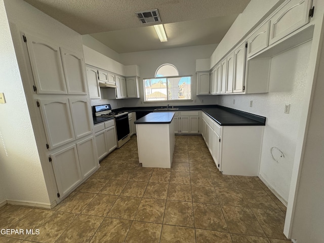 kitchen with white range with gas cooktop, a textured ceiling, a center island, sink, and white cabinetry