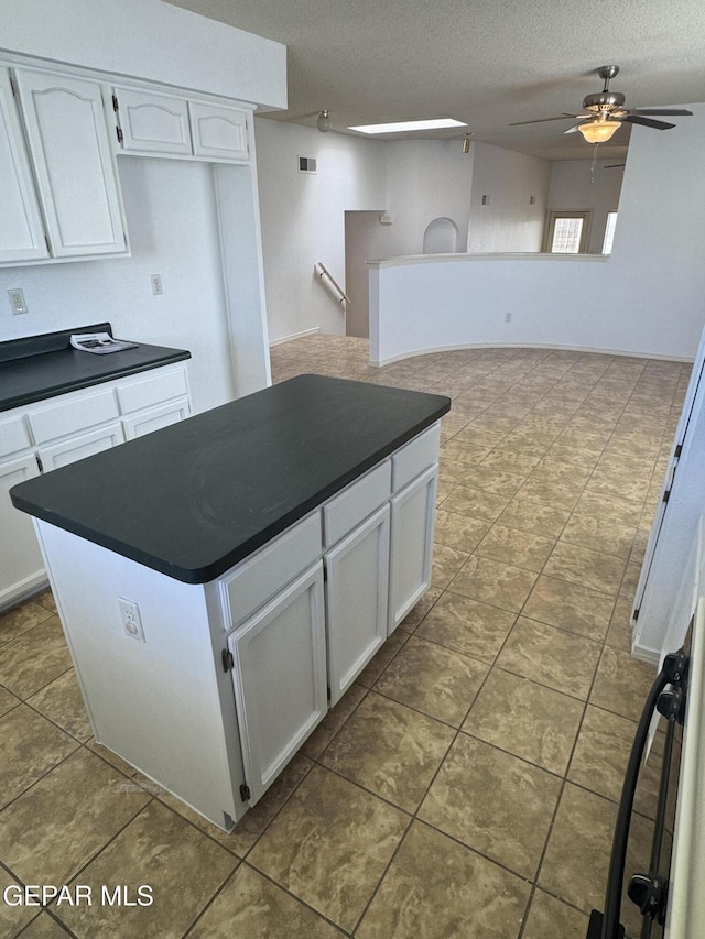 kitchen featuring ceiling fan, a textured ceiling, and white cabinets