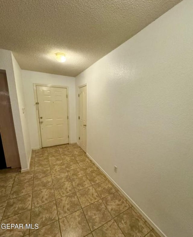 corridor with tile patterned flooring and a textured ceiling