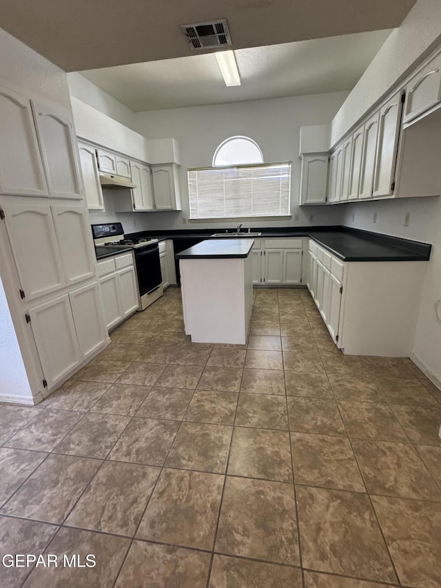 kitchen featuring white cabinetry, a center island, range with gas stovetop, sink, and dark tile patterned flooring