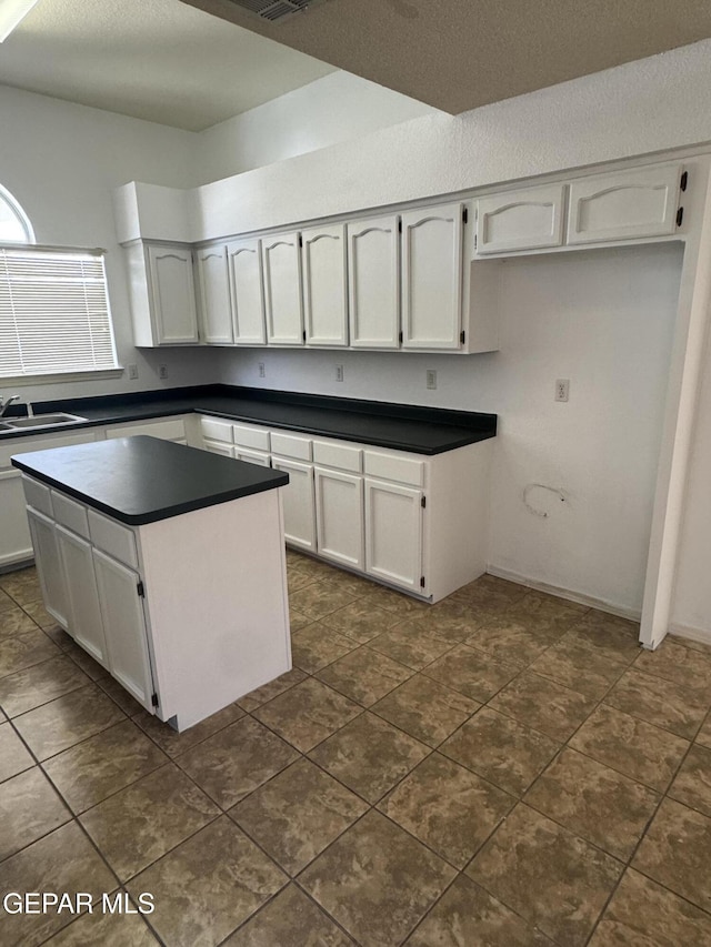 kitchen featuring sink, a kitchen island, and white cabinets