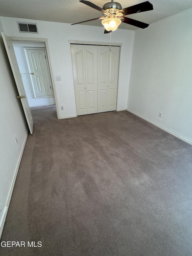 unfurnished bedroom with a textured ceiling, a closet, carpet, and ceiling fan