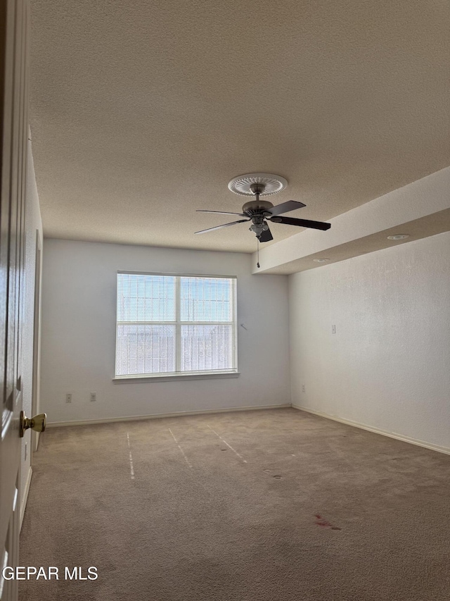 spare room with ceiling fan, light carpet, and a textured ceiling