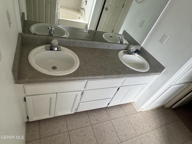 bathroom featuring vanity, a washtub, and tile patterned floors