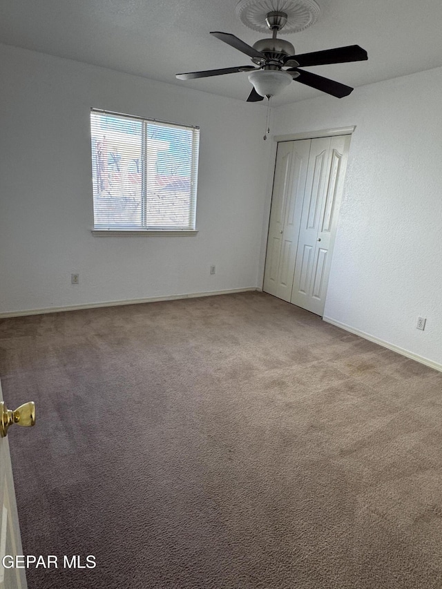 unfurnished bedroom featuring ceiling fan, carpet, and a closet