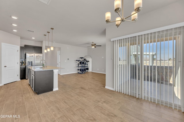 kitchen with a center island with sink, visible vents, open floor plan, pendant lighting, and ceiling fan with notable chandelier