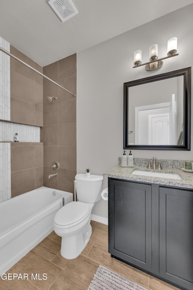 bathroom with baseboards, visible vents, toilet, bathtub / shower combination, and vanity