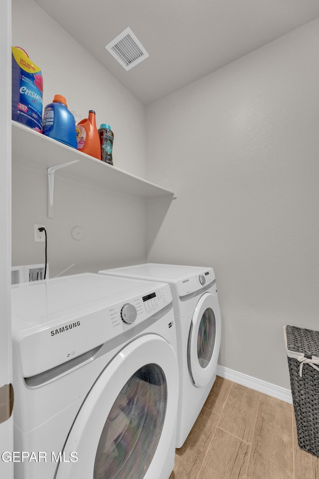 clothes washing area featuring visible vents, light wood-type flooring, laundry area, independent washer and dryer, and baseboards