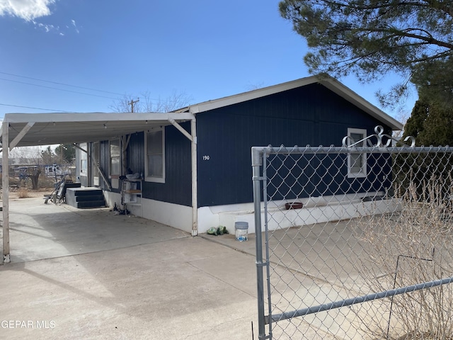 view of side of home featuring an attached carport, fence, and driveway