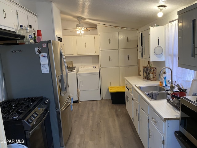 kitchen with stainless steel appliances, light countertops, white cabinetry, separate washer and dryer, and a sink