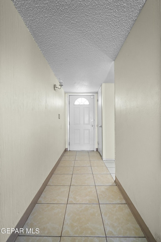 hall with a textured ceiling and light tile patterned floors