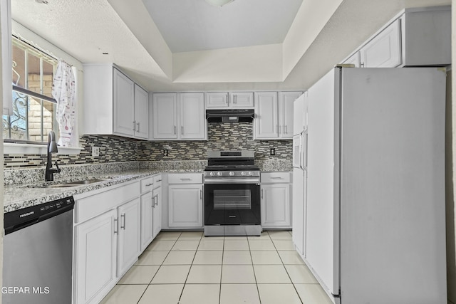 kitchen featuring light stone countertops, stainless steel appliances, decorative backsplash, and light tile patterned floors