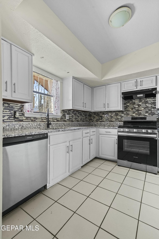 kitchen with white cabinets, tasteful backsplash, stainless steel appliances, and light tile patterned floors