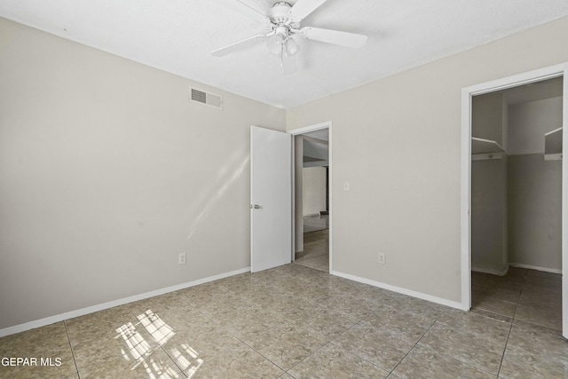 unfurnished bedroom with ceiling fan, a closet, a walk in closet, and tile patterned floors