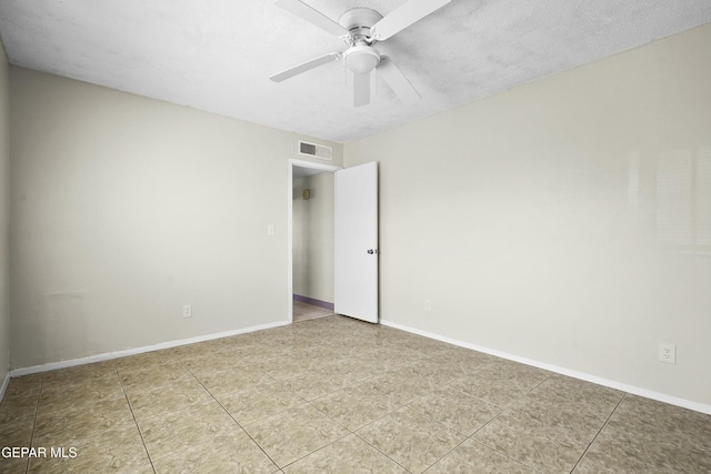 empty room featuring a textured ceiling, ceiling fan, and tile patterned floors