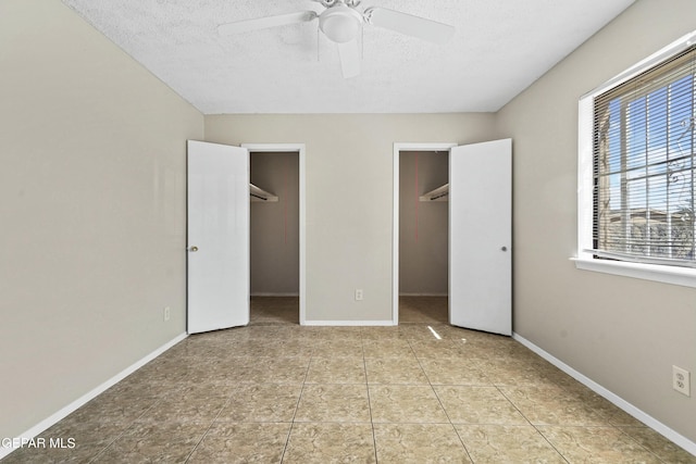 unfurnished bedroom featuring ceiling fan, light tile patterned flooring, a walk in closet, and a textured ceiling