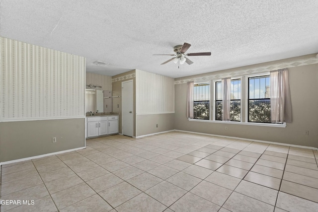 tiled empty room with ceiling fan and a textured ceiling