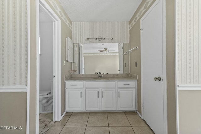 bathroom featuring tile patterned flooring, toilet, a textured ceiling, ceiling fan, and vanity