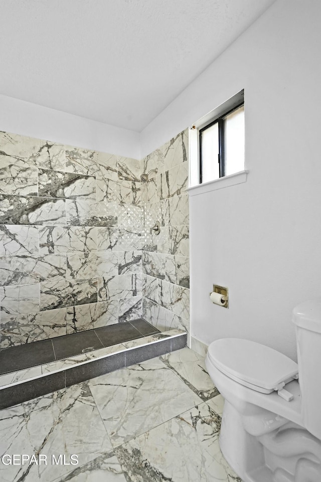 bathroom featuring a tile shower and toilet