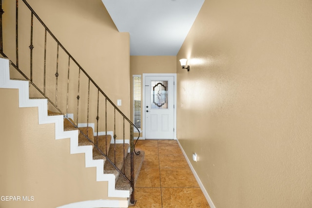 entryway with light tile patterned floors, stairway, and baseboards