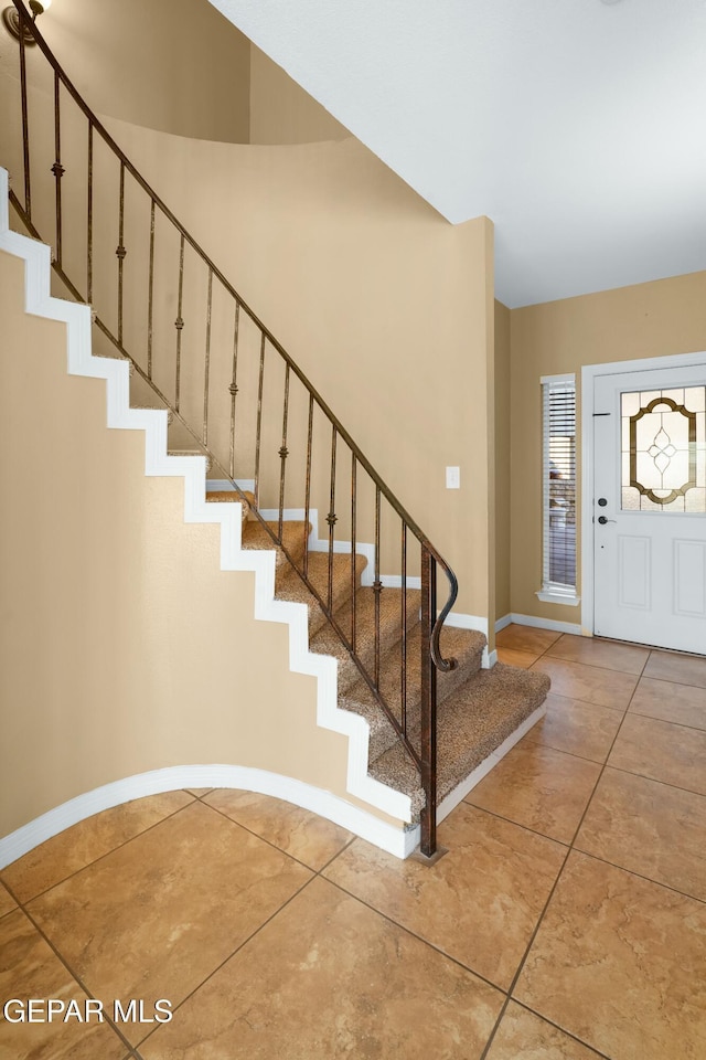 tiled foyer featuring stairway and baseboards