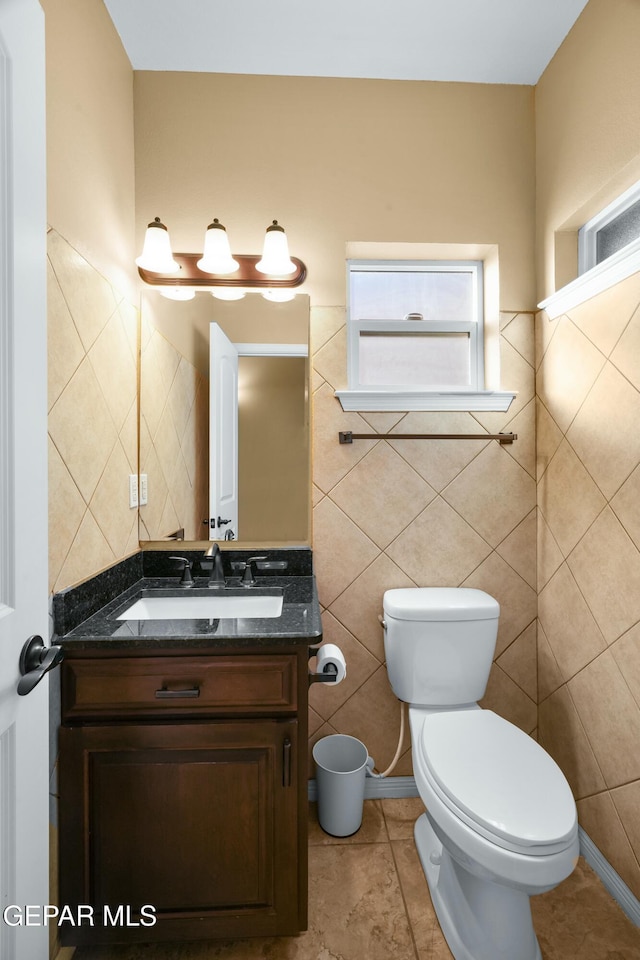 half bath featuring toilet, tile patterned flooring, and vanity