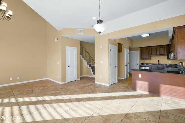 kitchen with pendant lighting, dark countertops, visible vents, a sink, and range