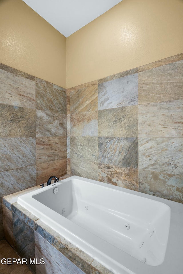 bathroom with a jetted tub and tile walls