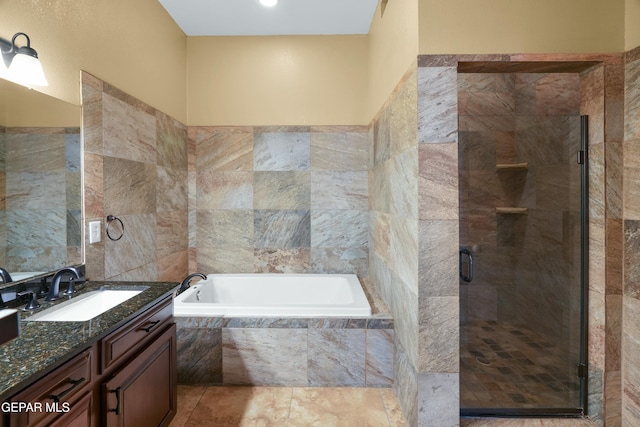 full bath with a stall shower, a garden tub, tile patterned flooring, vanity, and tile walls