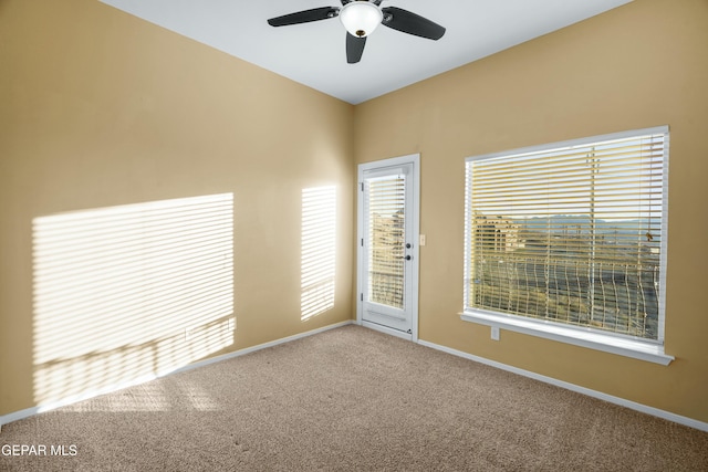 carpeted spare room featuring ceiling fan and baseboards