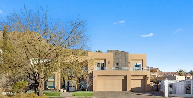 pueblo revival-style home with a garage and a balcony