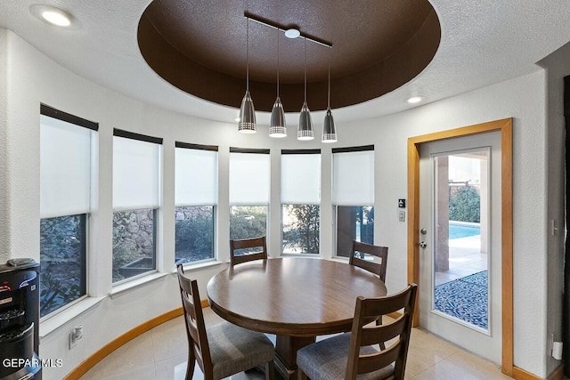 tiled dining room featuring a tray ceiling and a textured ceiling