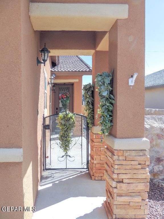 view of exterior entry with a tiled roof, a gate, and stucco siding