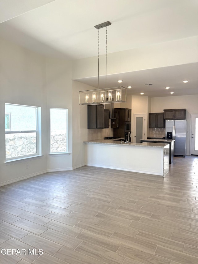 3872 Surmise St, El Paso, TX 79938 - kitchen featuring tasteful backsplash, a peninsula, appliances with stainless steel finishes, light wood finished floors, and baseboards