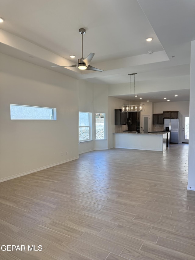 3872 Surmise St, El Paso, TX 79938 - unfurnished living room featuring baseboards, recessed lighting, light wood-style floors, a tray ceiling, and ceiling fan