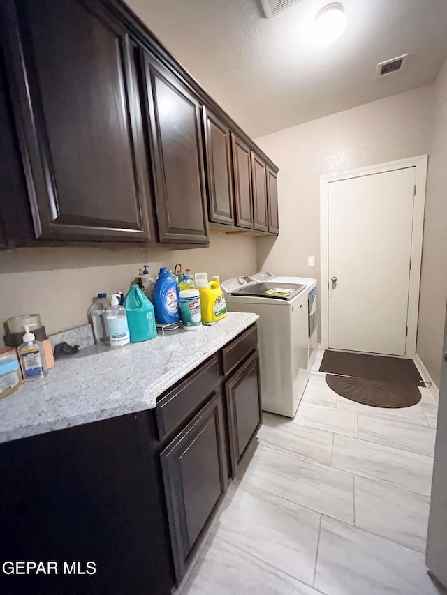 clothes washing area featuring washing machine and dryer and cabinets