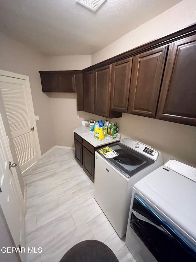 clothes washing area with cabinets and washing machine and clothes dryer