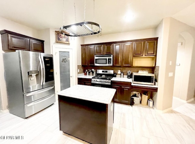 3165 Destiny Point Dr, El Paso, TX 79938 - kitchen with appliances with stainless steel finishes, arched walkways, dark brown cabinetry, and a kitchen island
