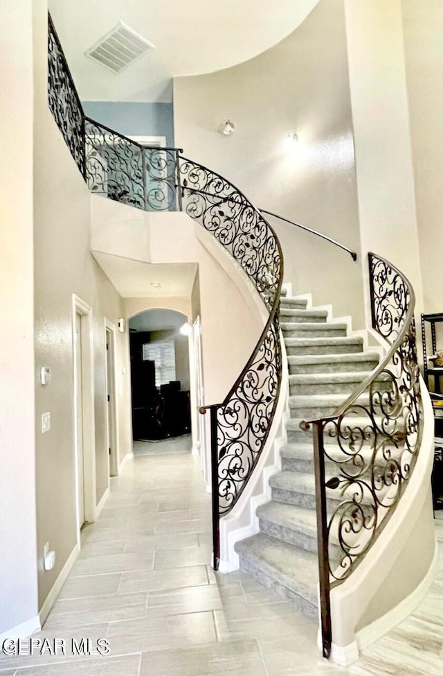 3165 Destiny Point Dr, El Paso, TX 79938 - staircase with baseboards, wood finish floors, a high ceiling, visible vents, and arched walkways