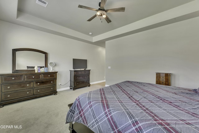 bedroom with ceiling fan, a raised ceiling, and light carpet