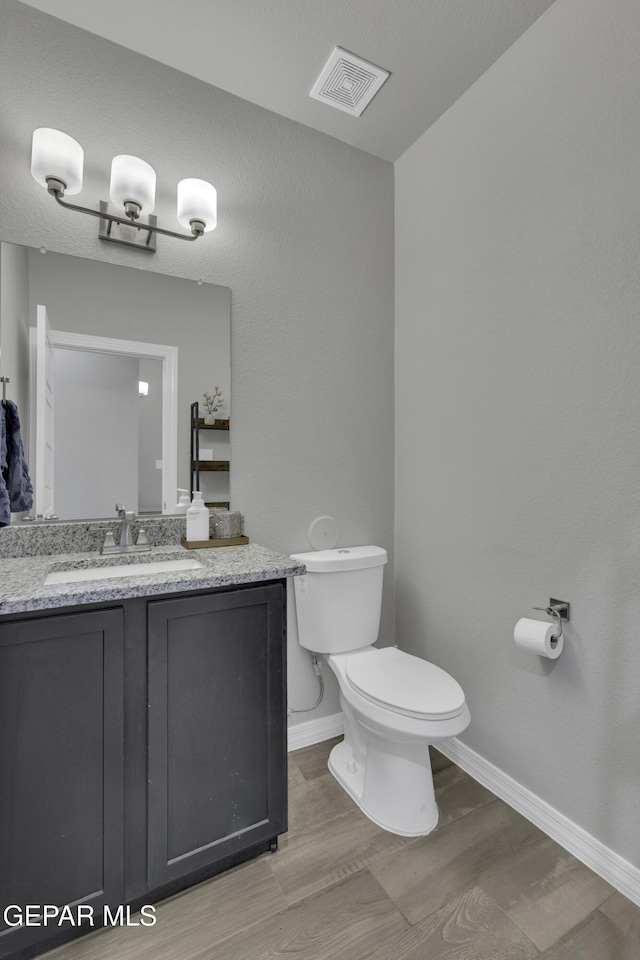 bathroom with wood-type flooring, vanity, and toilet