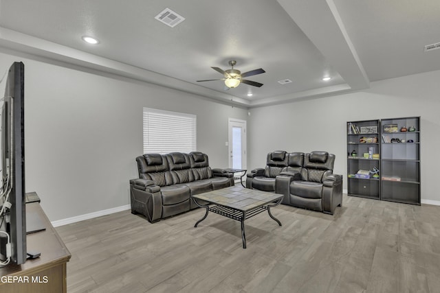 living room with a tray ceiling, light hardwood / wood-style flooring, and ceiling fan